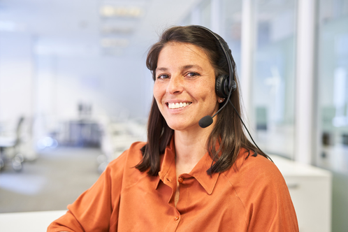 Mitarbeiterin mit Headset in einem modernen Büro, lächelnd